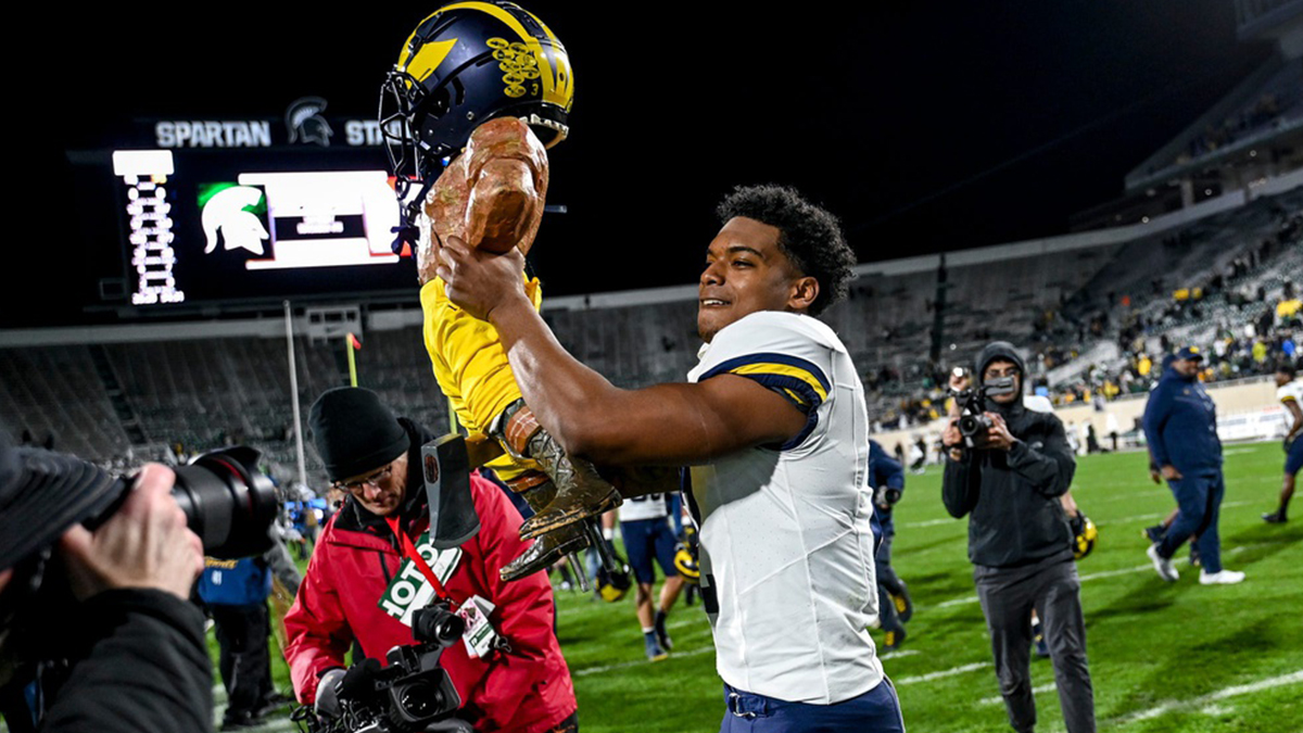 Michigan's Will Johnson celebrates with the Paul Bunyan trophy after beating Michigan State