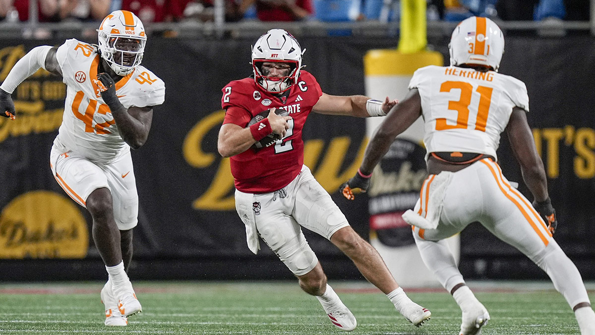 North Carolina State Wolfpack quarterback Grayson McCall (2) runs with the football as Tennessee Volunteers defensive lineman Tyre West (42) and defensive lineman Caleb Herring (31) defend during the second half at the Dukes Mayo Classic at Bank of America Stadium.