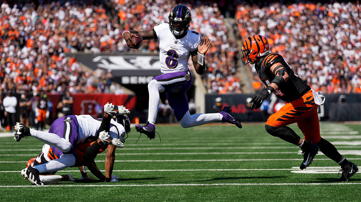 Baltimore Ravens quarterback Lamar Jackson (8) leaps away from Cincinnati Bengals defensive end Sam Hubbard (94) on a keeper in the first quarter of the NFL Week 5 game between the Cincinnati Bengals and Baltimore Ravens at Paycor Stadium in downtown Cincinnati on Sunday, Oct. 6, 2024. The Bengals led 17-14 at halftime.