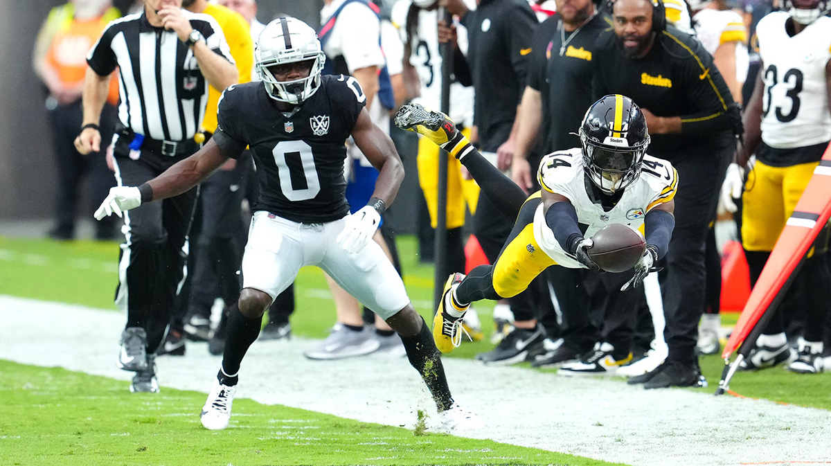 Pittsburgh Steelers wide receiver George Pickens (14) dives for extra yardage after making a catch in front of Las Vegas Raiders cornerback Jakorian Bennett (0) during the first quarter at Allegiant Stadium
