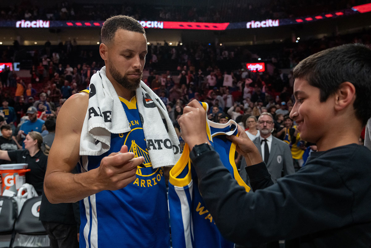 Golden State Warriors point guard Stephen Curry (30) signs a jersey for a fan after a game against the Portland Trailblazers at Moda Center.
