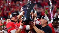 Utah Utes head coach Kyle Whittingham and quarterback Cameron Rising (7) lift the PAC-12 Football Championship trophy following the victory against the Southern California Trojans at Allegiant Stadium.