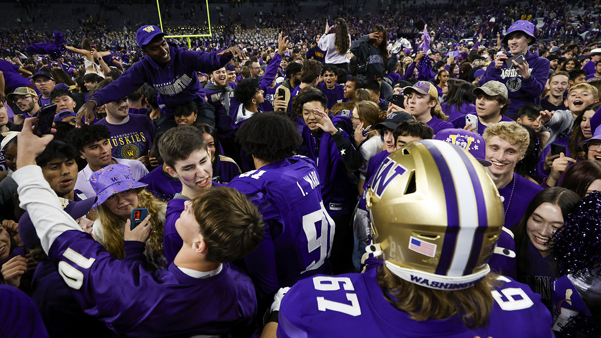 Washington Huskies fans rush the field to congratulate players following a victory against the Michigan Wolverines at Alaska Airlines Field at Husky Stadium.