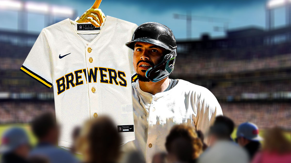 Willy Adames smiling while wearing a blank uniform, while holding a Brewers uniform