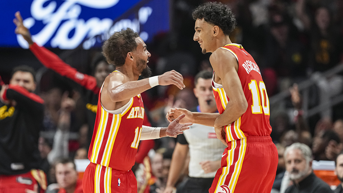Atlanta Hawks forward Zaccharie Risacher (10) reacts with guard Trae Young (11) after making a three point basket for his first points in the NBA against the Brooklyn Nets during the first half at State Farm Arena.