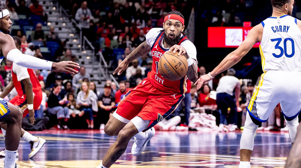 New Orleans Pelicans forward Brandon Ingram (14) dribbles against Golden State Warriors guard Stephen Curry (30) and guard Buddy Hield (7) during first half at Smoothie King Center.