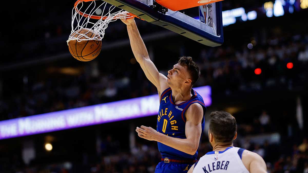 Denver Nuggets guard Christian Braun (0) dunks the ball as Dallas Mavericks forward Maxi Kleber (42) looks on in the first quarte at Ball Arena. 