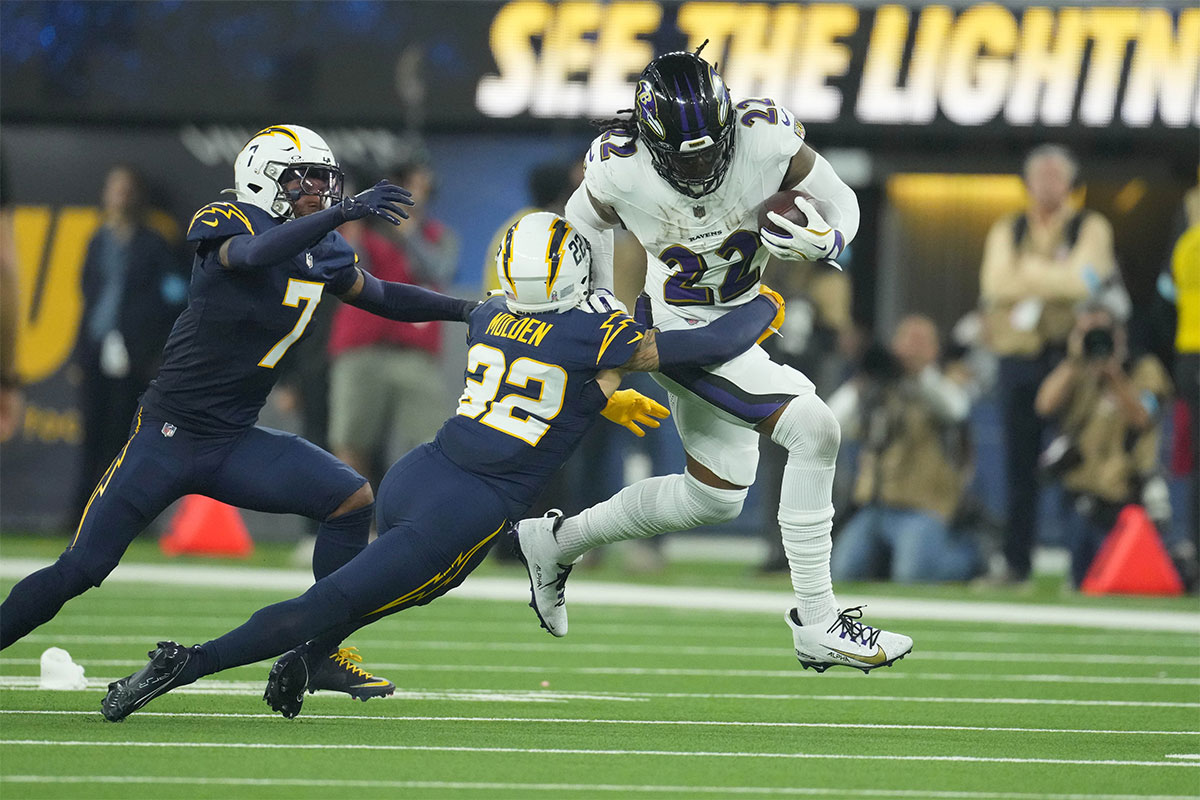 Baltimore Ravens running back Derrick Henry (22) carries the ball against Los Angeles Chargers cornerback Kristian Fulton (7) and cornerback Elijah Molden (22) in the second half at SoFi Stadium.