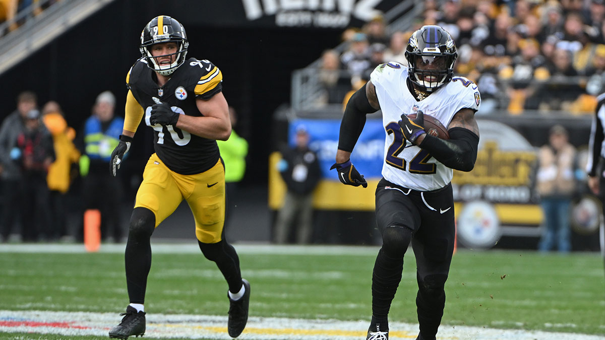 Baltimore Ravens running back Derrick Henry (22) gains yardage while being chased by Pittsburgh Steelers linebacker T.J. Watt (90) during the second quarter at Acrisure Stadium.