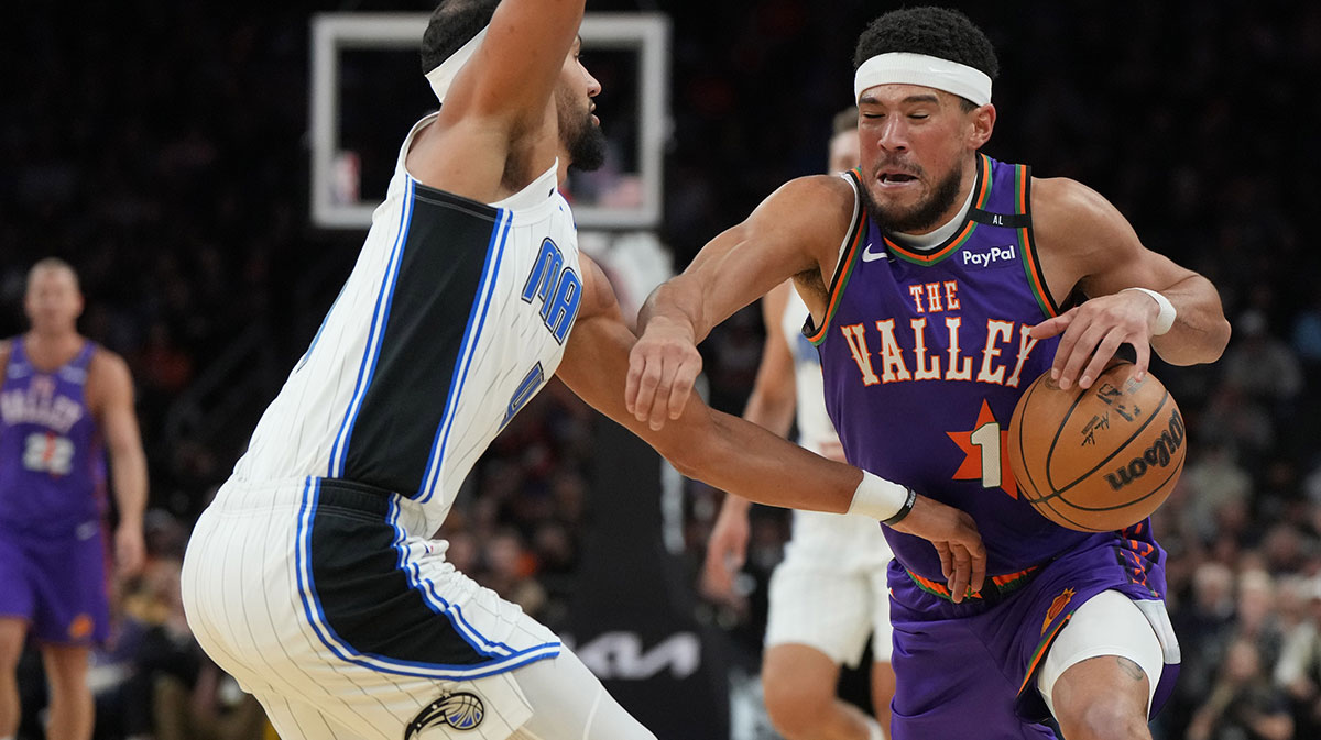 Phoenix Suns guard Devin Booker (1) drives on Orlando Magic guard Jalen Suggs (4) during the first half of an NBA game at Footprint Center.