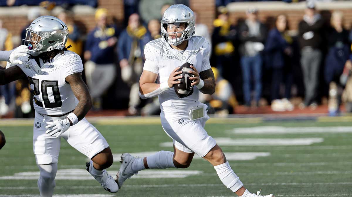 Oregon Ducks quarterback Dillon Gabriel (8) rolls out to pass in the first half against the Michigan Wolverines at Michigan Stadium.