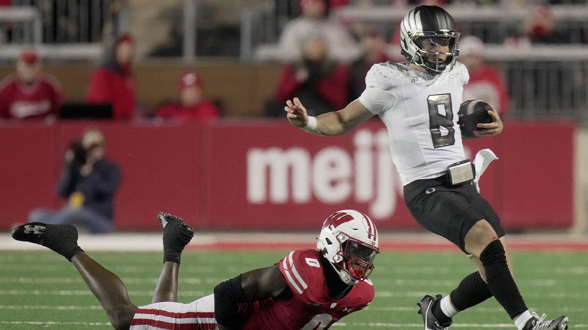 Oregon quarterback Dillon Gabriel (8) avoids a tackle by Wisconsin linebacker John Pius (0) while running for a first down during the fourth quarter of their game Saturday, November 16, 2024 at Camp Randall Stadium in Madison, Wisconsin. Oregon beat Wisconsin 16-13.