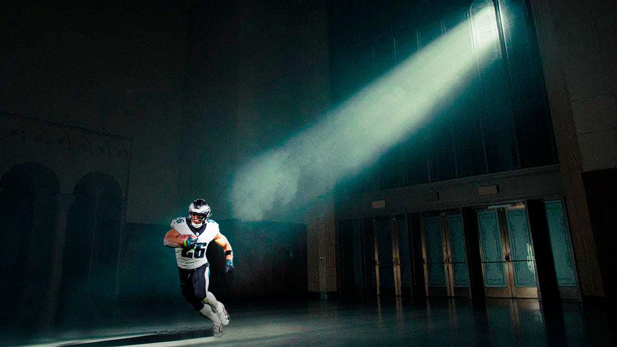 Replace the figure with Saquon Barkkley (Eagles) rushing with the ball and under a ray of light.