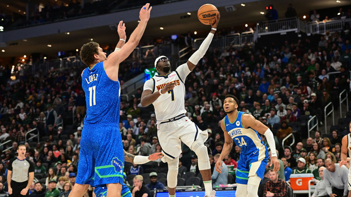 Denver Nuggets guard Reggie Jackson (7) takes a shot between Milwaukee Bucks center Brook Lopez (11) and forward Giannis Antetokounmpo (34) in the third quarter at Fiserv Forum.