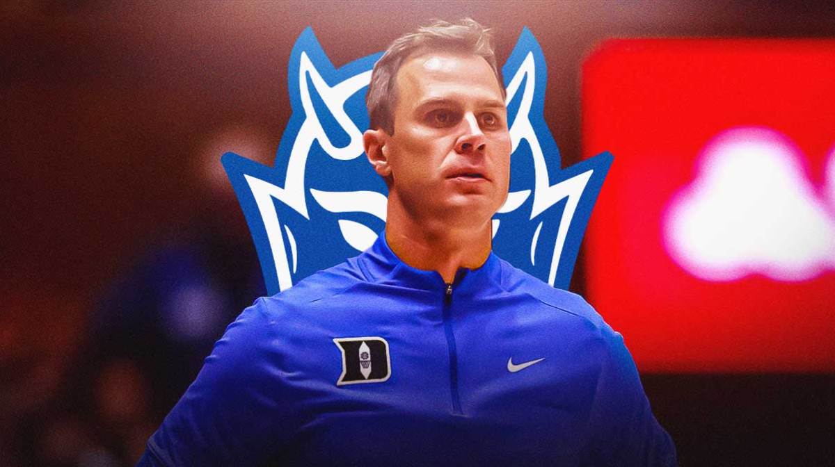 Duke basketball coach Jon Scheyer with the Duke Blue Devils logo in the background, Wofford win