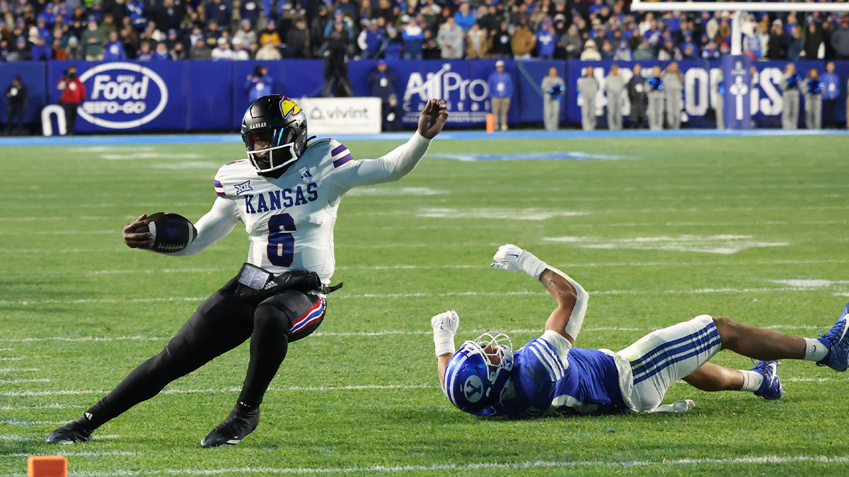 Kansas Jayhawks quarterback Jalon Daniels (6) is tripped up by Brigham Young Cougars linebacker Jack Kelly (17) during the second quarter at LaVell Edwards Stadium.