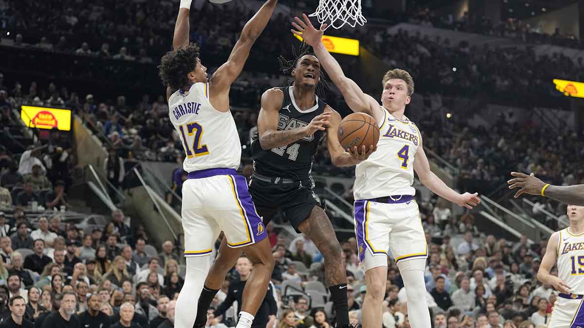 San Antonio Spurs guard Devin Vassell (24) drives to the basket between la Los Angeles Lakers guard Max Christie (12) and forward Dalton Knecht (4) during the first half at Frost Bank Center.