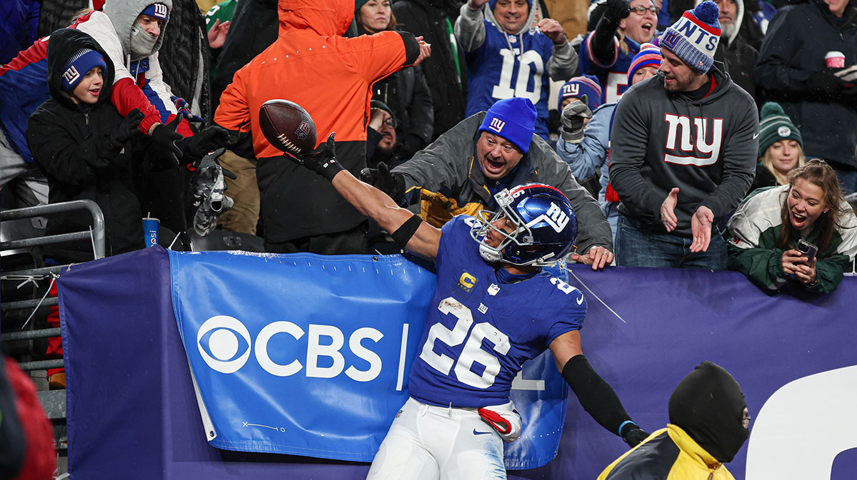New York Giants running back Saquon Barkley (26) gives the game ball to a young fan after scoring his second touchdown of the game during the first half against the Philadelphia Eagles at MetLife Stadium. 
