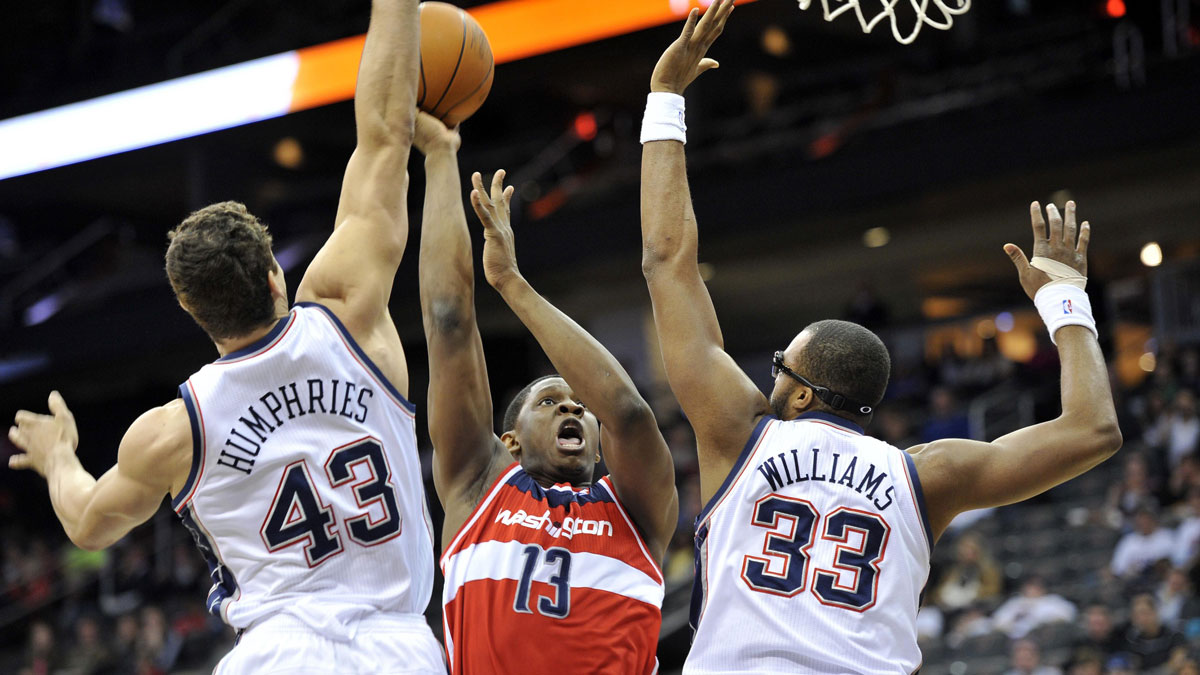 Washington Wizards center Kevin Seraphin (13) puts up a shot over New Jersey Nets forward Kris Humphries (43) and forward Shelden Williams (33) during the first half at the Prudential Center. 