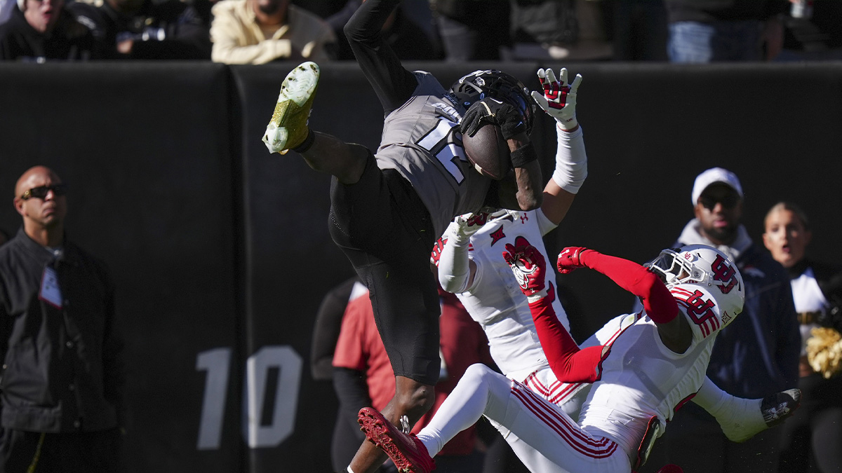 Colorado Buffaloes wide receiver Travis Hunter (12) pulls in a reception over Utah Utes cornerback Smith Snowden (2) and cornerback Cameron Calhoun (4) in the second quarter at Folsom Field.