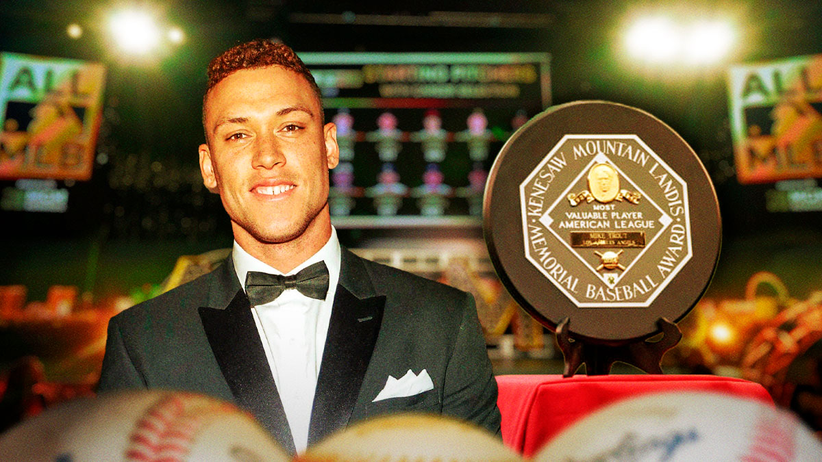 Yankees Aaron Judge standing next to the AL MVP award, the second of his career