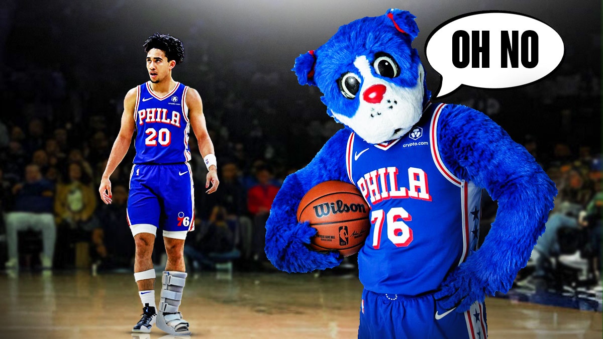 Franklin the 76ers Dog mascott with a text bubble reading "Oh no" next to Jared McCain with a large white cast on his left leg in front of the 76ers court.