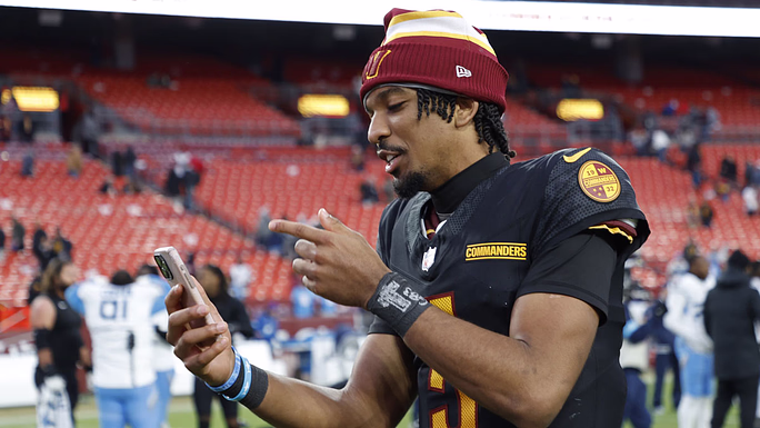 Dec 1, 2024; Landover, Maryland, USA; Washington Commanders quarterback Jayden Daniels (5) records a social media video while leaving the field after the Commanders' game against the Tennessee Titans at Northwest Stadium.