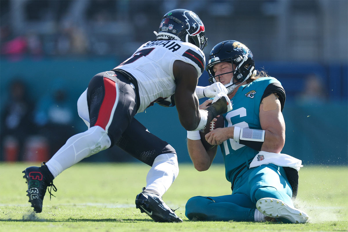 Jacksonville Jaguars quarterback Trevor Lawrence (16) slides down in front of Houston Texans linebacker Azeez Al-Shaair (0) in the second quarter in the second quarter at EverBank Stadium.