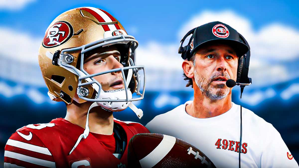 Brock Purdy looking up at the sky as he walks off the field, standing next to head coach Kyle Shanahan.
