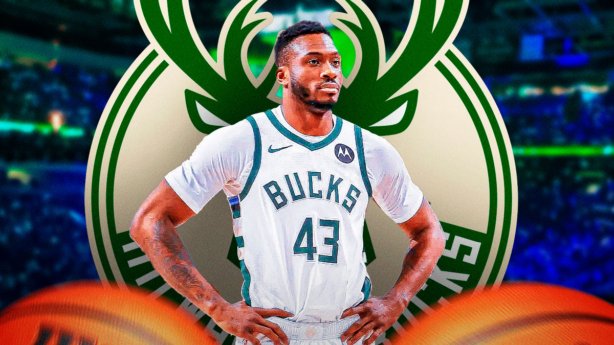 Thanasis Antetokounmpo with a Bucks logo next to him and Fiserv Forum behind him
