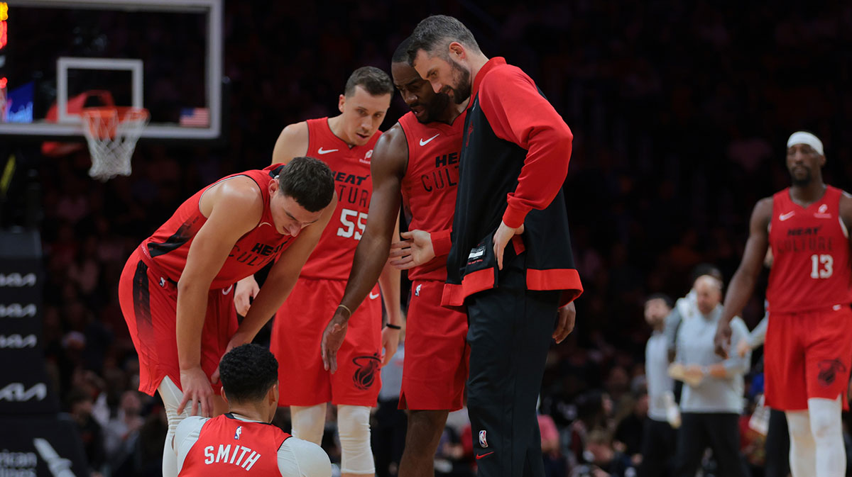 Miami Heat guard Dru Smith (12) is checked on by forward Kevin Love (42) forward Nikola Jovic (5) and guard Alec Burks (18) after an injury against the Brooklyn Nets during the second quarter at Kaseya Center.