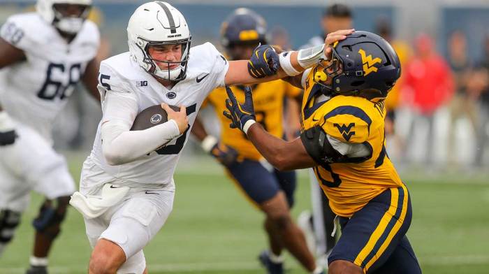Penn State Nittany Lions quarterback Drew Allar (15) runs the ball and stiff arms West Virginia Mountaineers linebacker Josiah Trotter (40) during the fourth quarter at Mountaineer Field at Milan Puskar Stadium.