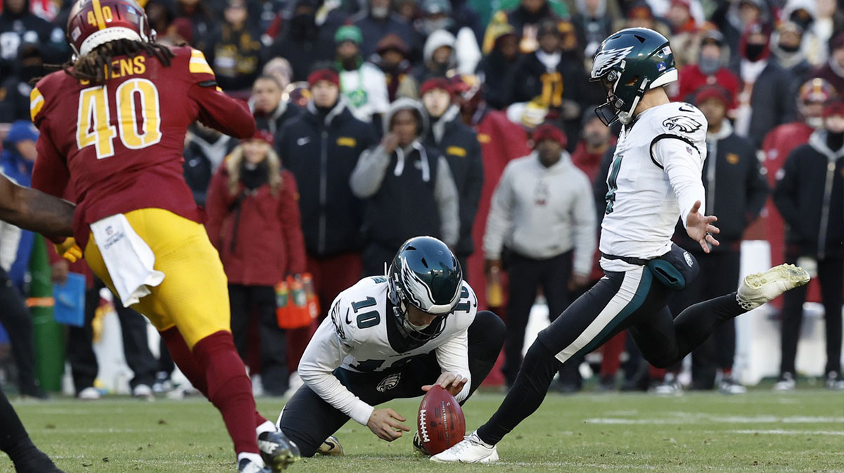 Philadelphia Eagles place kicker Jake Elliott (4) kicks a go ahead field goal as Washington Commanders safety Tyler Owens (40) defends during the fourth quarter at Northwest Stadium. 