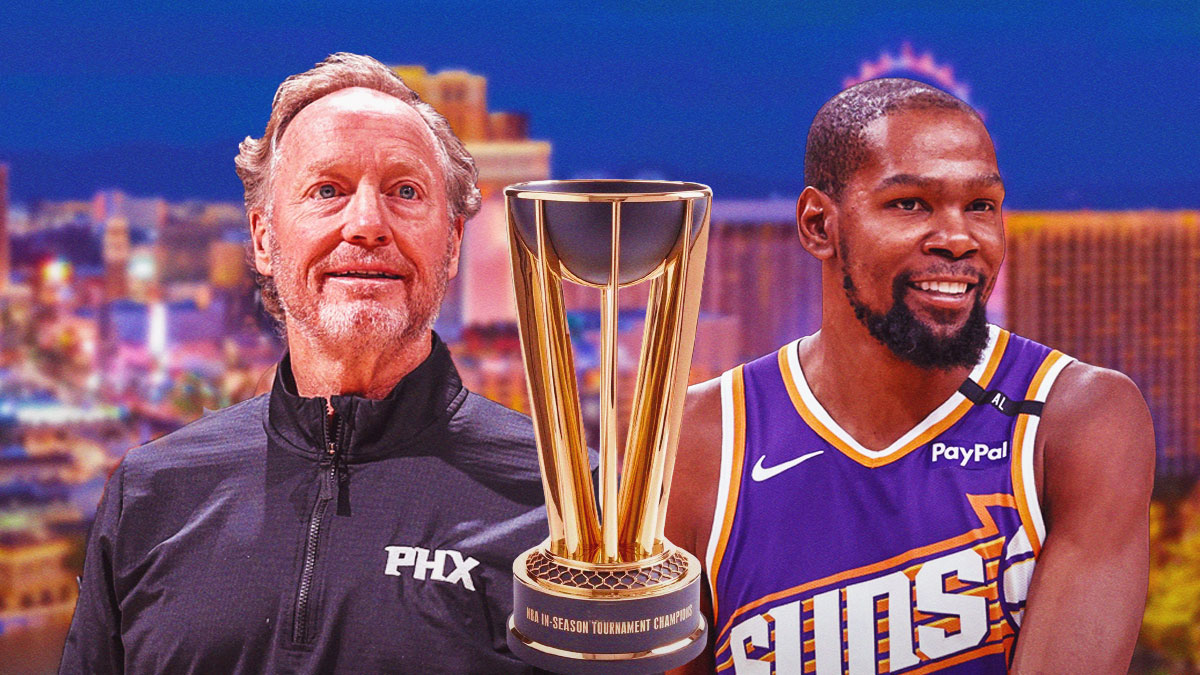 Suns forward Kevin Durant and head coach Mike Budenholzer smiling with the NBA Cup trophy next to them, and a background of the skyline of Las Vegas.