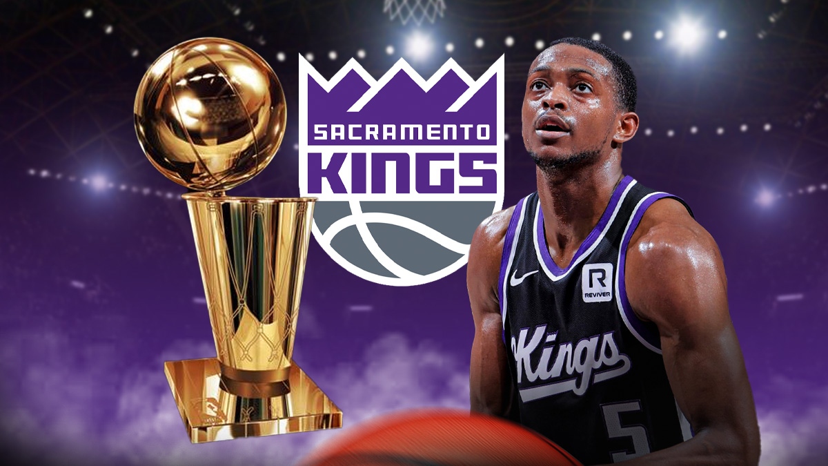 De'Aaron Fox looking at the Larry O'Brien trophy. Kings logo in the background.