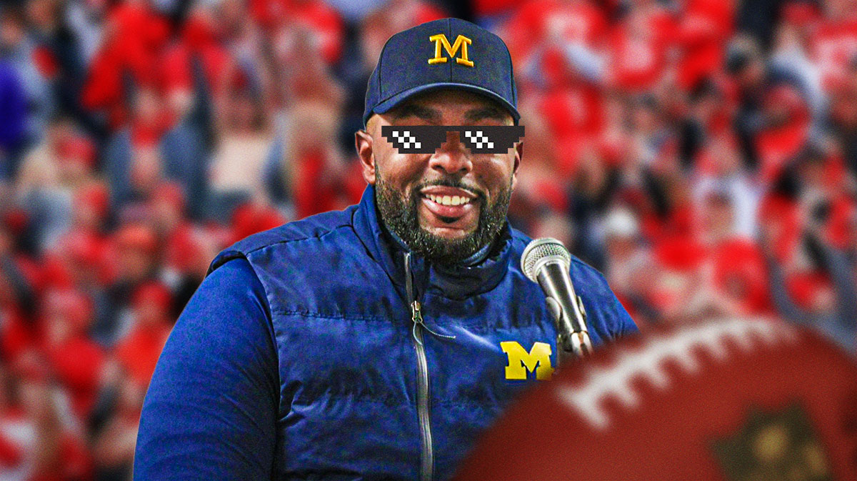 Happy Michigan Football coach Sherrone Moore with the "deal with it" glasses in front of upset Ohio State fans