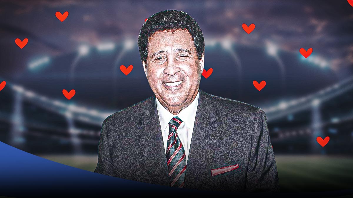 NFL/NCAA broadcaster Greg Gumbel smiling with hearts in background. Background is football field.