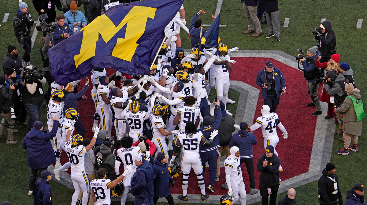 Michigan football players plant their team’s flag at midfield following Saturday’s NCAA Division I football game against the Ohio State Buckeyes at Ohio Stadium. Ohio State lost to the Michigan Wolverines 13-10.