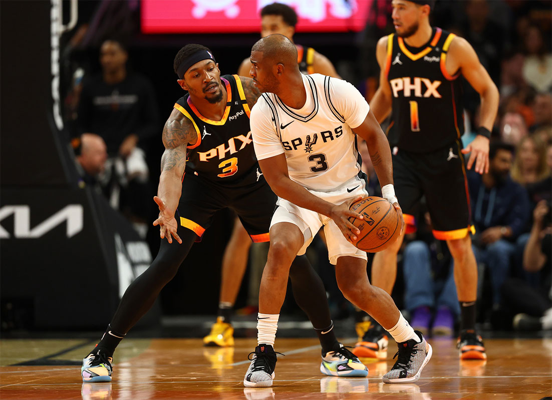 San Antonio Spurs guard Chris Paul (right) controls the ball against Phoenix Suns guard Bradley Beal in the second half of an NBA Cup game at Footprint Center.