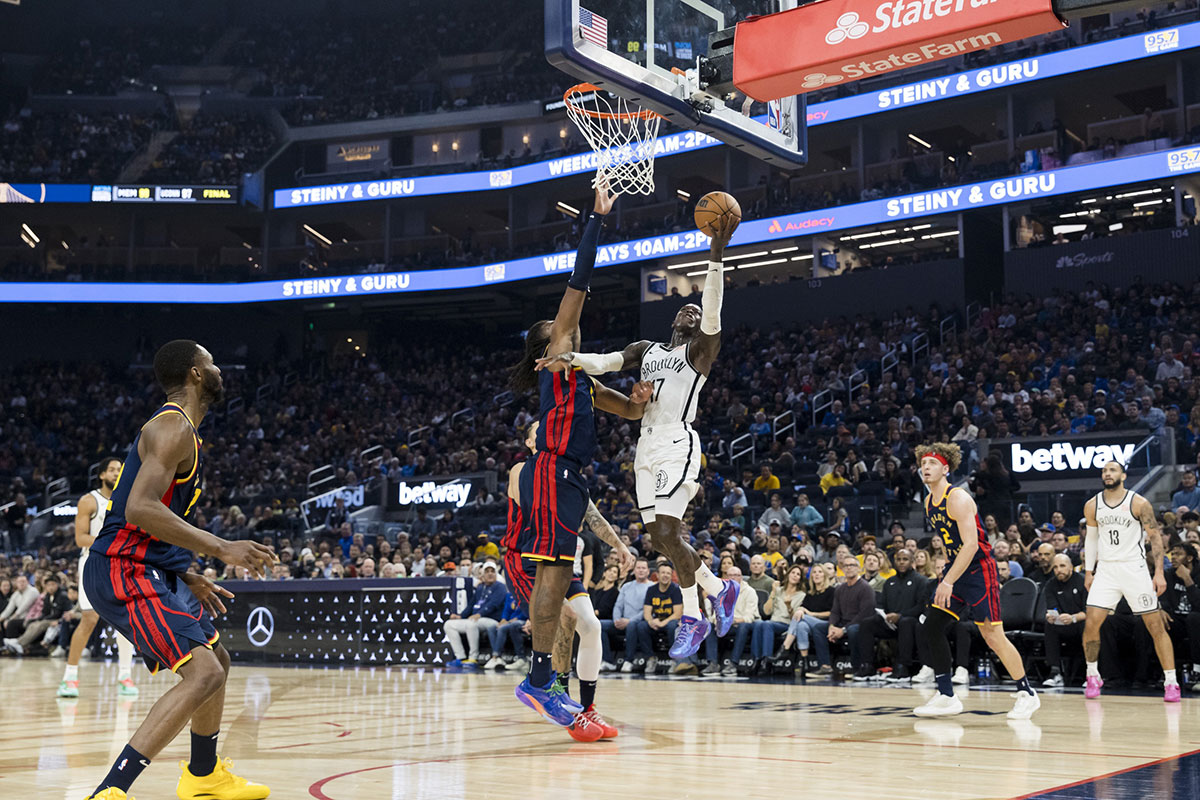 Brooklyn Nets guard Dennis Schroder (17) shoots as Golden State Warriors forward Kevon Looney (5) defends during the first half at Chase Center.