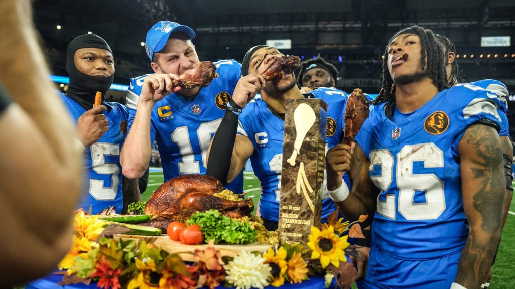 Lions quarterback Jared Goff (16), defensive tackle DJ Reader (98), wide receiver Amon-Ra St. Brown (14), running back Jahmyr Gibbs (26) and linebacker Al-Quadin Muhammad (69) celebrate their win against the Bears with a turkey drumstick Thanksgiving Day in Detroit.