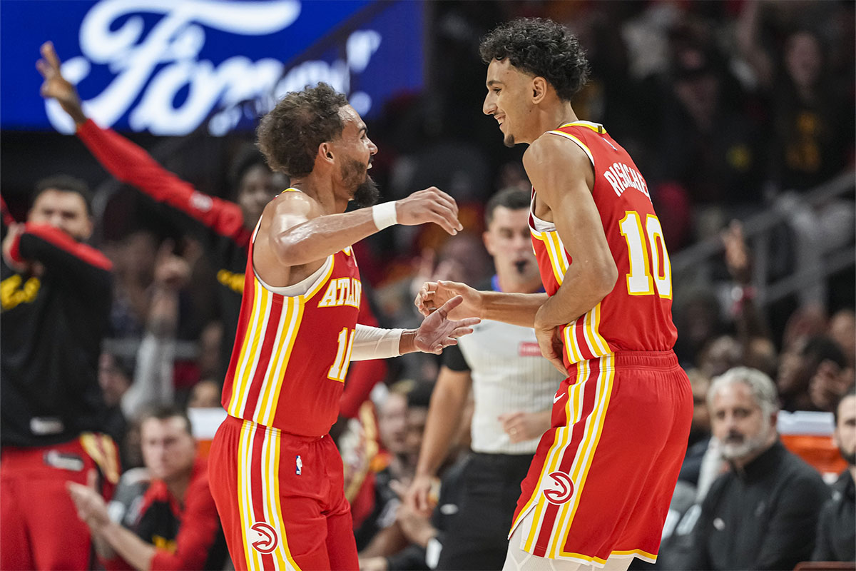 Atlanta Hawks forward Zaccharie Risacher (10) reacts with guard Trae Young (11) after making a three point basket for his first points in the NBA against the Brooklyn Nets during the first half at State Farm Arena.