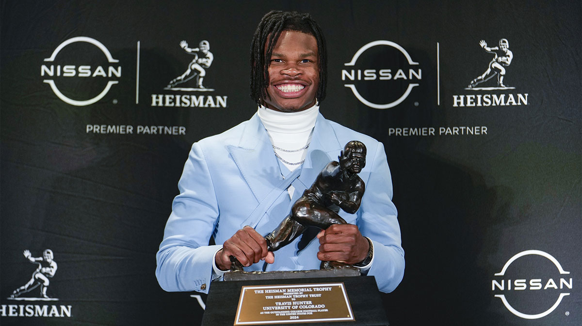 https://wp.clutchpoints.com/wp-content/uploads/2024/12/Travis-Hunter-holds-up-the-Heisman-Trophy.jpg