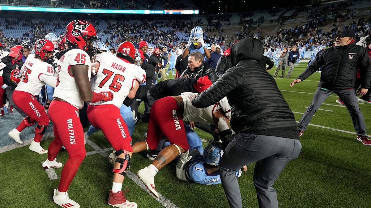 North Carolina Tar Heels players and North Carolina State Wolfpack players fight as State tries to put a Wolfpack flag at midfield after the game at Kenan Memorial Stadium.