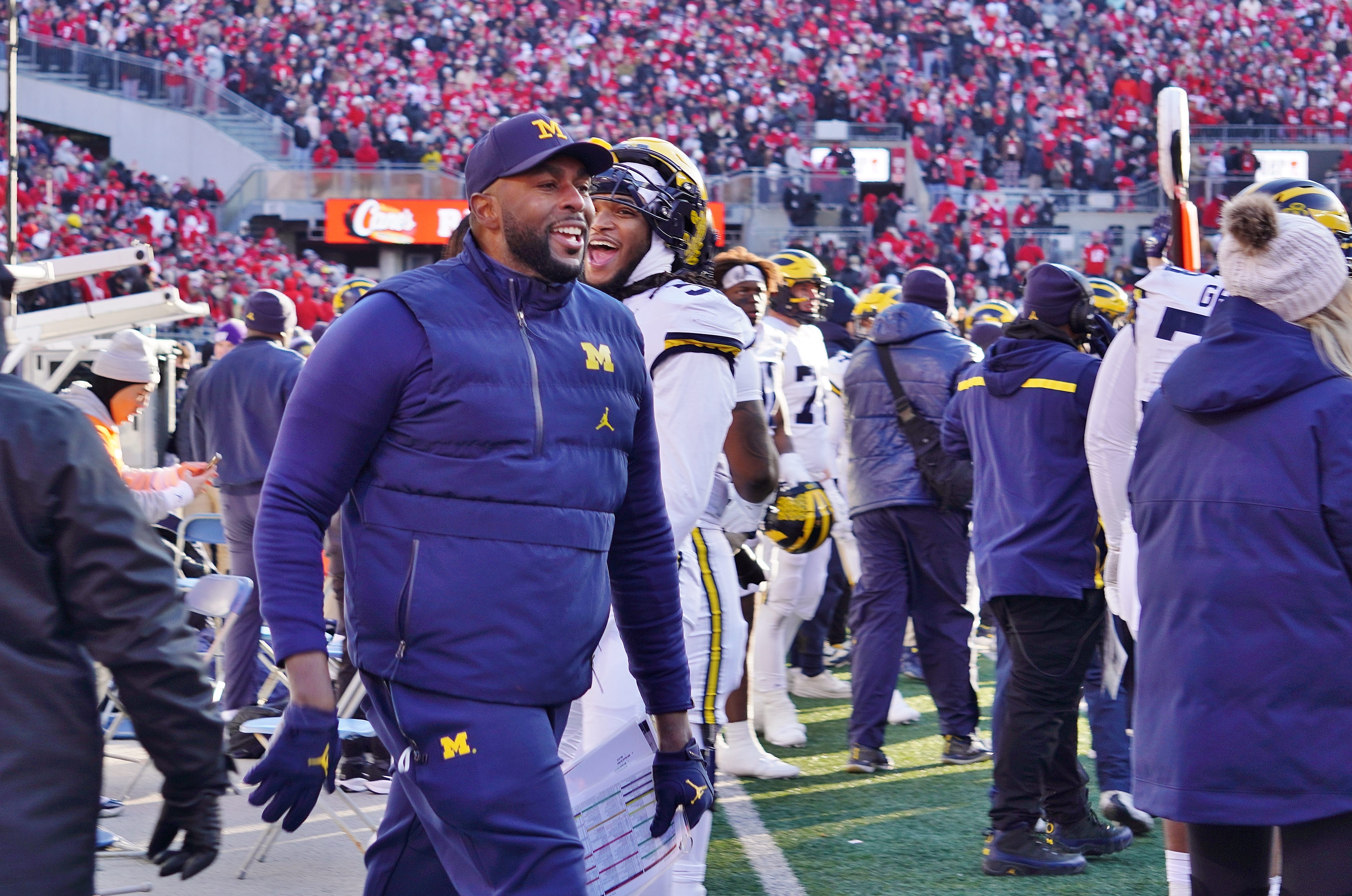 Michigan Wolverines coach Sherrone Moore returns to the sideline after waving goodbye to Ohio State fans at the end of his team's 13-10 victory.