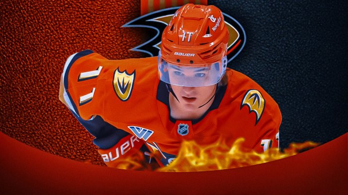 Trevor Zegras looking happy with fire around him, Anaheim Ducks logo, hockey rink in background