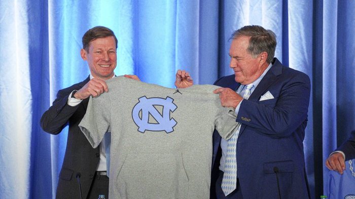 North Carolina Tar Heels chancellor Lee Roberts presents a cut off sweatshirt to new head coach Bill Belichick at Loudermilk Center for Excellence.