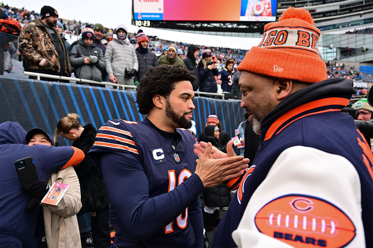 Chicago Bears quarterback Caleb Williams (18) greets his father Carl Williams on the sidelines before a game against the Detroit Lions at Soldier Field.