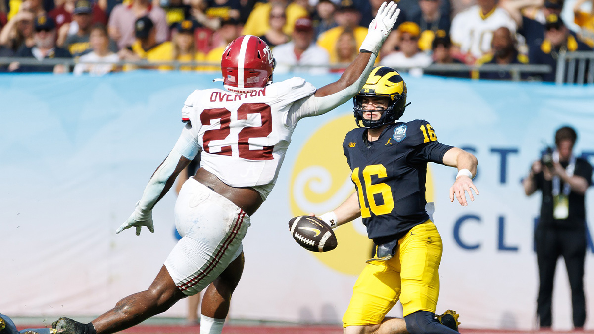 Michigan Wolverines quarterback Davis Warren (16) jukes Alabama Crimson Tide defensive lineman LT Overton (22) during the first half at Raymond James Stadium.