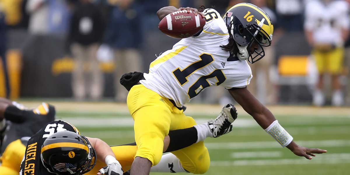 Tyler Nielsen trips up Michigan quarterback Denard Robinson in a game